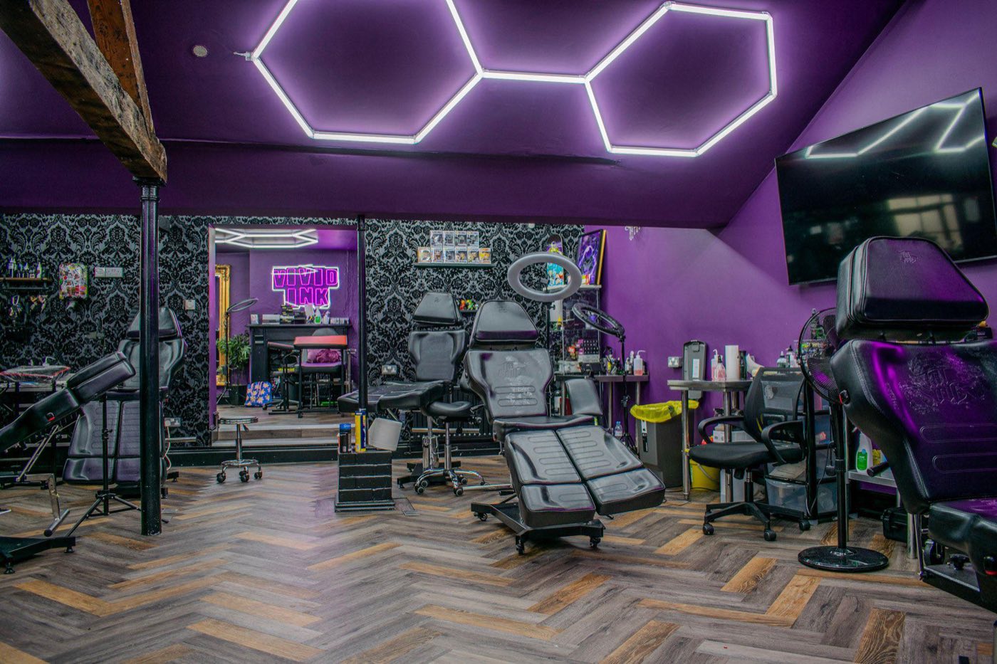 Inside the Vivid Ink studio on Iron Gate, with tattoo stations and the studio's neon sign