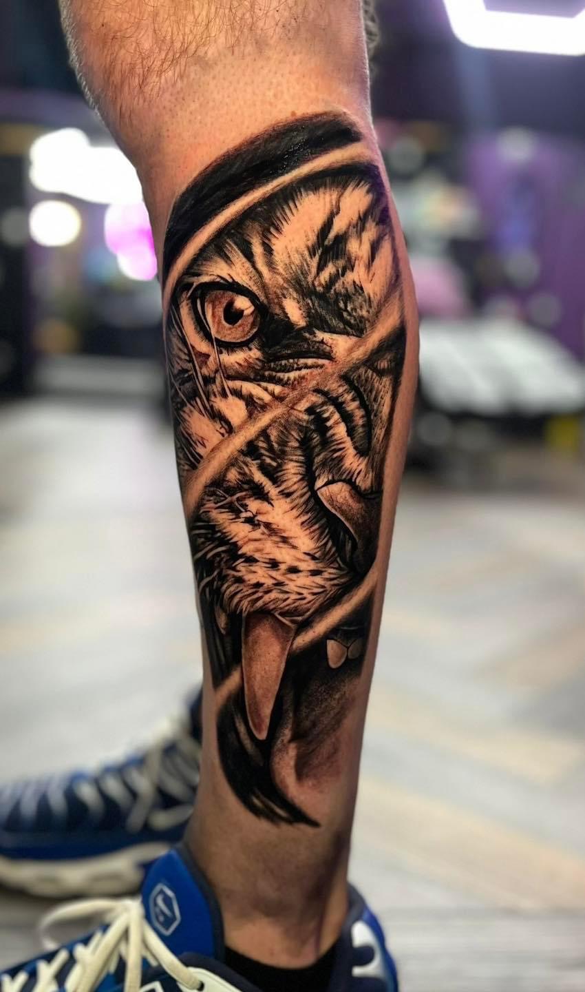 Realism tattoo of a tiger eye and face on a lower leg