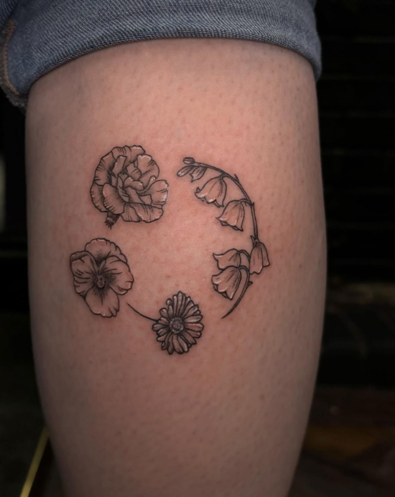 Delicate fineline floral tattoo in black ink on a forearm